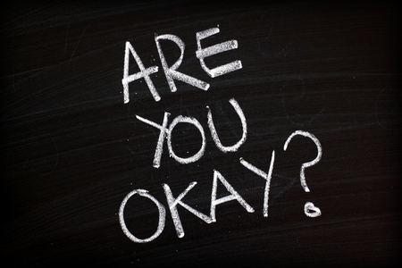 The question Are You Okay written by hand in white chalk on a blackboardの写真素材