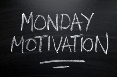 The words Monday Motivation written by hand in white chalk on a blackboard as a reminderの写真素材