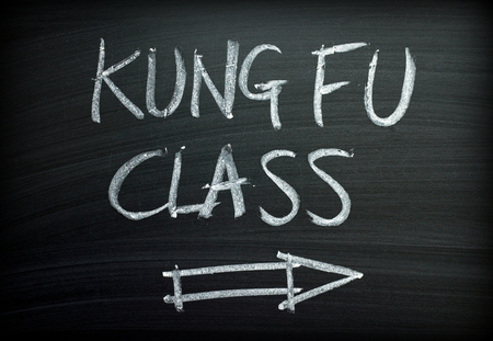 The words Kung Fu Class written by hand in white chalk on a blackboard signの写真素材