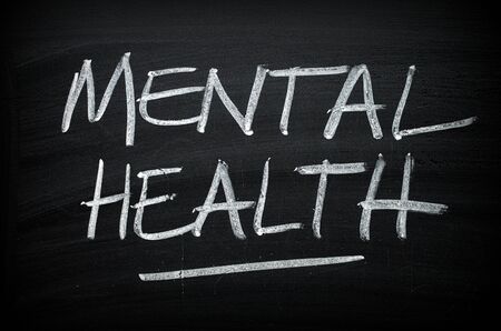 The words Mental Health written by hand on a blackboard as an awareness messageの写真素材