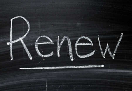 The word Renew written by hand in white chalk on a blackboardの写真素材