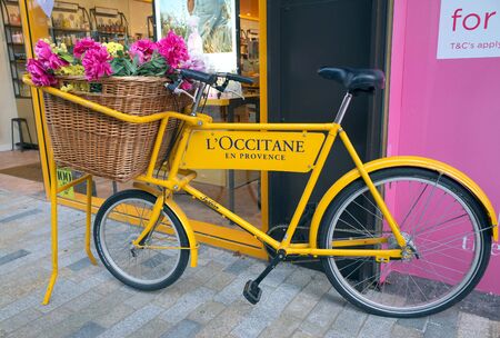 Bracknell, England - February 18, 2020: A bicycle with a basket of flowers painted with the brand name and colors of L'Occitane outside their store in Bracknell Englandのeditorial素材