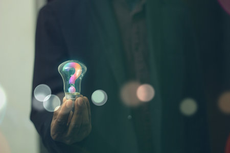 Man holding a light bulb with glowing question mark inside the bulb. Business man holding bulb with...