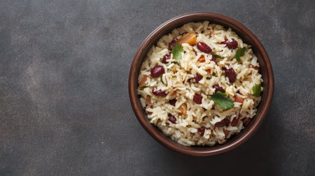 A vibrant bowl of rice mixed with beans and fresh herbs sits on a dark surface, creating an inviting meal perfect for any occasion.の素材