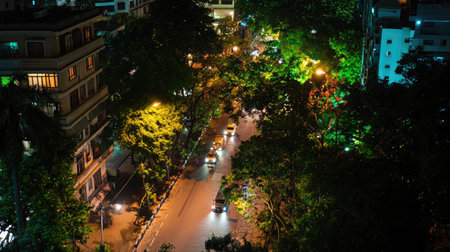 A captivating view of a city street at night, showcasing illuminated cars weaving through lush trees and softly lit buildings, capturing urban beauty.の素材