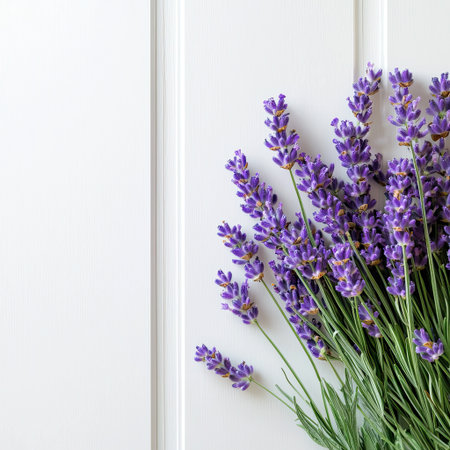 This stunning image features a vibrant arrangement of fresh purple flowers with delicate green leaves against a soft white background, ideal for decoration.の素材