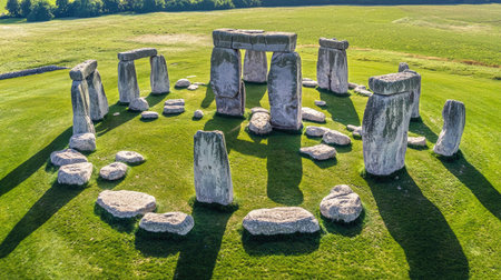 Aerial view of Stonehenge, an iconic prehistoric monument in England, showcasing its unique stone arrangement on verdant grass under a bright sky.の素材
