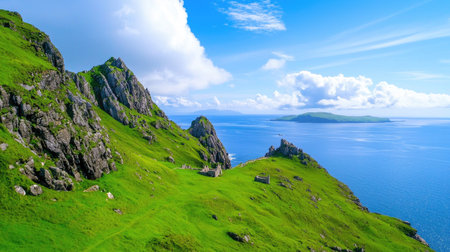 Breathtaking view of a coastal landscape featuring lush green mountains rising over calm blue waters under a bright sky dotted with clouds.の素材