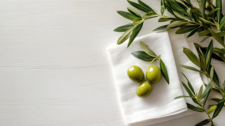 Explore the beauty of fresh green olives accompanied by olive branches on a white wooden table, perfect for culinary inspiration and healthy eating.の素材