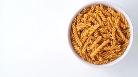 A simple bowl of rotini pasta, viewed from above on a white background with ample copy spaceの素材