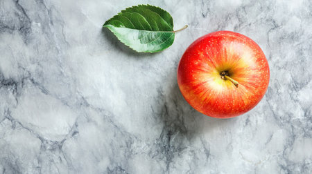 Fresh apple with a leaf, viewed from above on a smooth marble surface, with ample copy space for textの素材