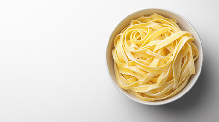 Creamy fettuccine pasta in a bowl, viewed from above on a plain white background with ample copy spaceの素材