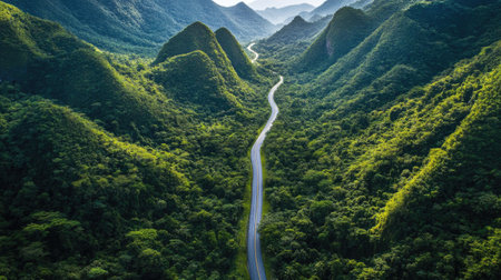 Aerial view of a scenic road cutting through towering mountain peaks and lush greenery. Perfect for travel guides and brochuresの素材
