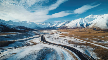 Aerial shot of a road winding through high-altitude terrain with snow-capped peaks. Perfect for winter travel and outdoor themesの素材