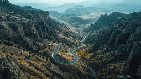 Top view of a serpentine road cutting through a rugged mountain landscape with open valleys. Ideal for adventure and nature themesの素材