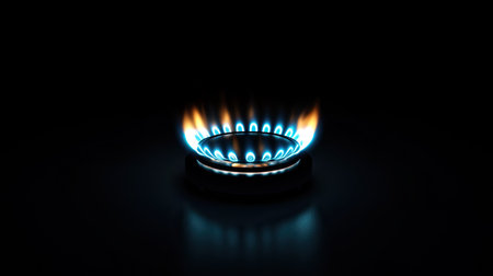 Natural gas burner with a bright blue flame, isolated against a dark, black background. No people, copy spaceの素材