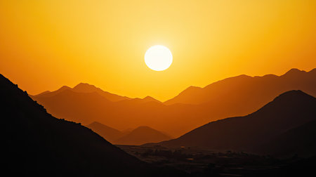 Golden sun setting behind distant mountains, with ample copy space.の素材