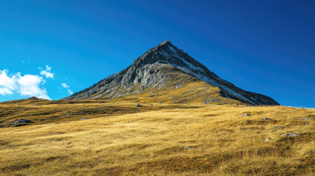 Majestic mountain peak under a clear blue sky, with a wide-open space for text.の素材