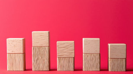 This image features a series of minimalist wooden blocks arranged in ascending order against a vibrant red background. The blocks symbolize growth and progress, making it perfect for business and educational themes.の素材