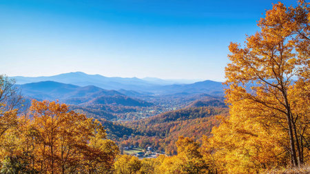 Golden autumn leaves blanketing mountain slopes with a clear blue sky aboveの素材