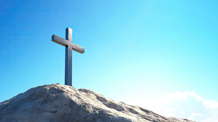 A majestic cross standing tall on a mountain peak under a clear blue sky, with room for inspirational text or messagesの素材