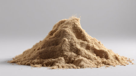A close-up of a fine light brown powder pile against a plain background, ideal for culinary or cosmetic applications, showcasing texture and detail.の素材