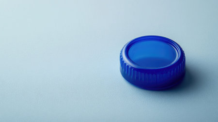 A detailed view of a blue plastic bottle cap resting on a soft background, perfect for concepts of recycling, minimalism, and beverage design.の素材