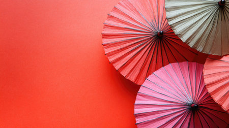This image features an artistic arrangement of colorful paper umbrellas resting on a bright red background, creating a vibrant and festive atmosphere.の素材