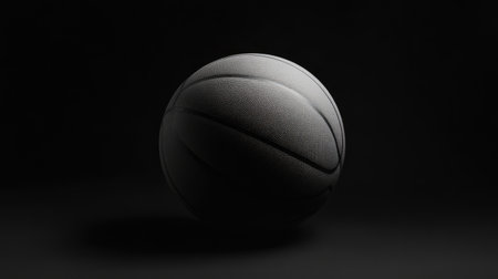 An artistic representation of a basketball illuminated against a dark backdrop, emphasizing its texture and shape, perfect for sports-related themes or fitness concepts.の素材