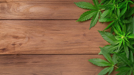 A vibrant arrangement of fresh green cannabis leaves on a rustic wooden surface, symbolizing organic lifestyle, health benefits, and natural beauty.の素材