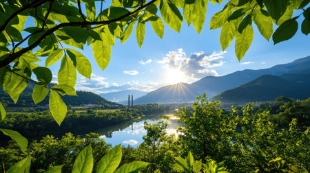 A stunning view featuring vibrant green leaves framing a tranquil river with soft sunlight casting gentle rays over distant mountains, creating a peaceful natural scene.の素材