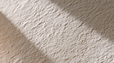 Close-up view of a light beige textured wall, highlighting unique patterns and subtle shadows, perfect for backgrounds or design projects.の素材