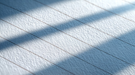 This close-up image showcases a finely textured paper surface, illuminated by gentle shadows and lined patterns, creating a serene backdrop for creative projects.の素材