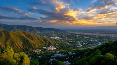 A stunning view of a sunset illuminating a picturesque valley and river, bordered by impressive mountains and rich greenery, creating a serene landscape.の素材