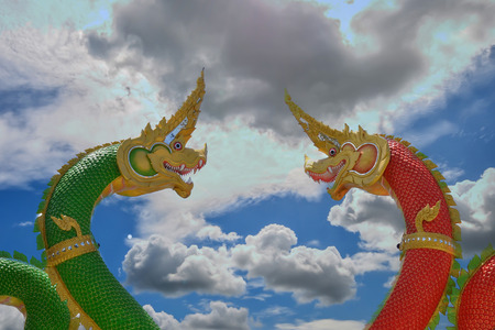 Two dragons in red and green on a backdrop of beautiful cloudsの写真素材