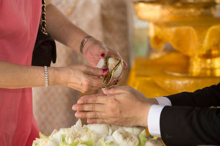 hands pouring blessing water into bride's bands, Thai wedding ceremonyの写真素材