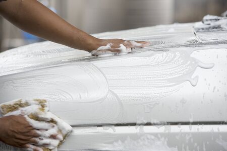 unidentified man worker washing white car on Blur backgroundの写真素材