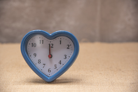 Blue heart shape watch on brown background.の写真素材