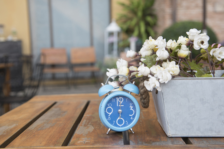 Blue clock with Artificial Flowers as a background or wallpaper.