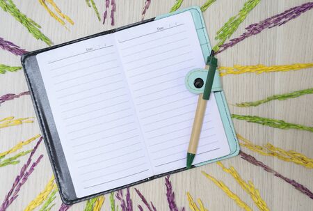 Top view with notebook, pen and dried rice grains on wooden floorの写真素材