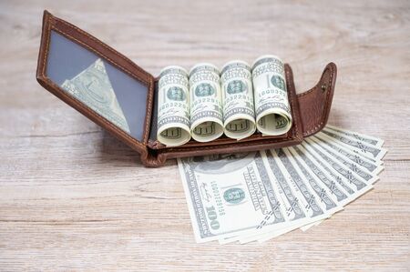 us dollar banknotes with brown leather wallet on the wooden floor backgroundの写真素材