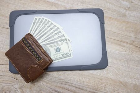Wooden desk with a top view, wallet with dollars and computersの写真素材
