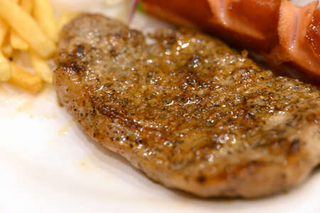 Black Pepper Pork Steak with Yellow French Fries and Sausageの写真素材
