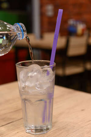 Pour the water from the bottle into the glass on the background of the dining tableの写真素材