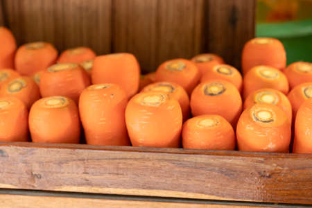 Carrots stacked in wooden boxes on a wooden backdropの写真素材