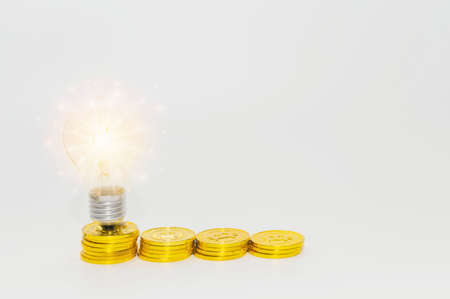 Stacking gold coins with light bulbs on business money saving inspiration concept background
