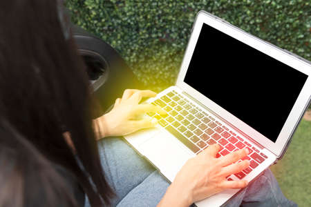 Young woman with a computer with a blank black screen with copy space and creative ideas and designsの写真素材