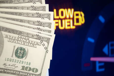 Dollar bank money coming from car fuel mileage dashboard concept closed on financial backgroundの写真素材