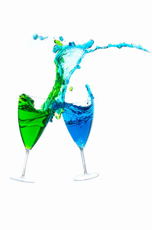 Cocktail glass with colorful liquor splashed at close distance, isolated on whiteの写真素材