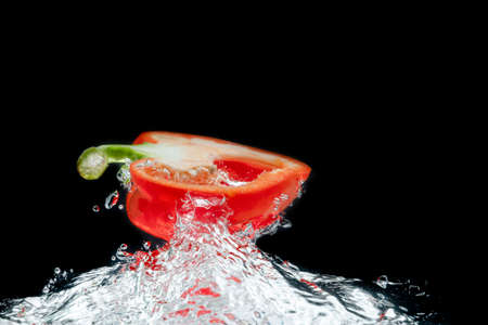 Splattered colored bell peppers splashed on a black background with a cut-out background.の写真素材
